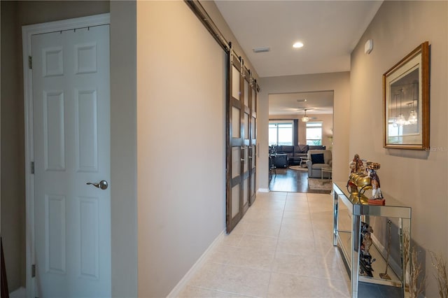 hall featuring light tile patterned floors and a barn door