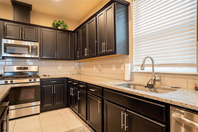 kitchen featuring tasteful backsplash, appliances with stainless steel finishes, sink, and light stone counters