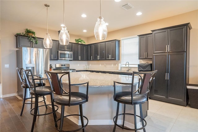 kitchen with appliances with stainless steel finishes, a kitchen island, and hanging light fixtures