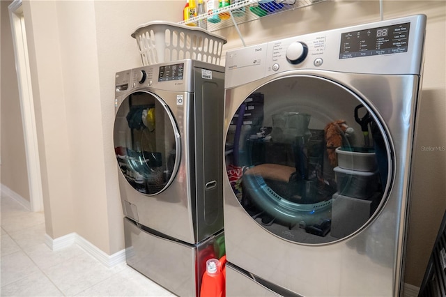 clothes washing area with washer and clothes dryer and light tile patterned floors