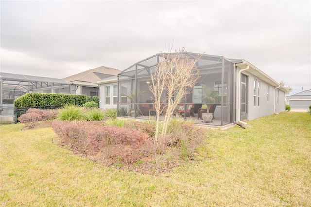 rear view of house featuring glass enclosure and a lawn