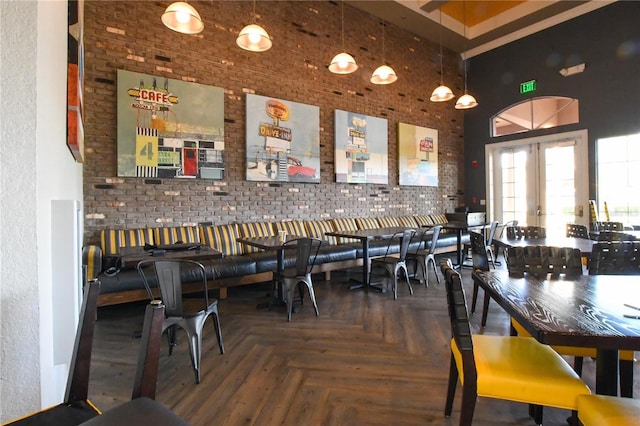 dining space featuring parquet floors, a towering ceiling, french doors, and brick wall