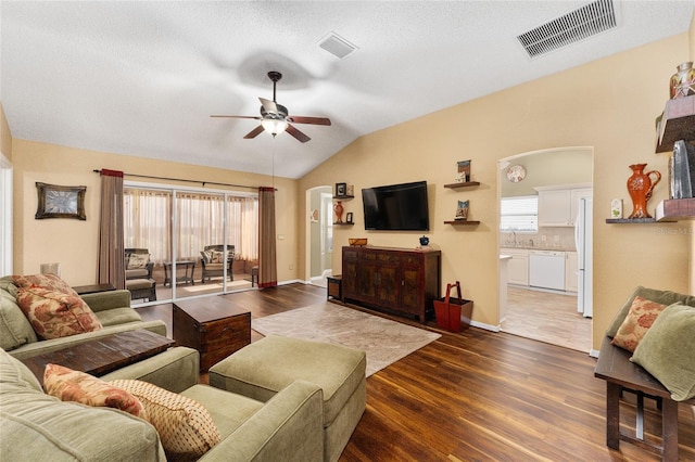 living room with dark hardwood / wood-style flooring, ceiling fan, vaulted ceiling, and a healthy amount of sunlight