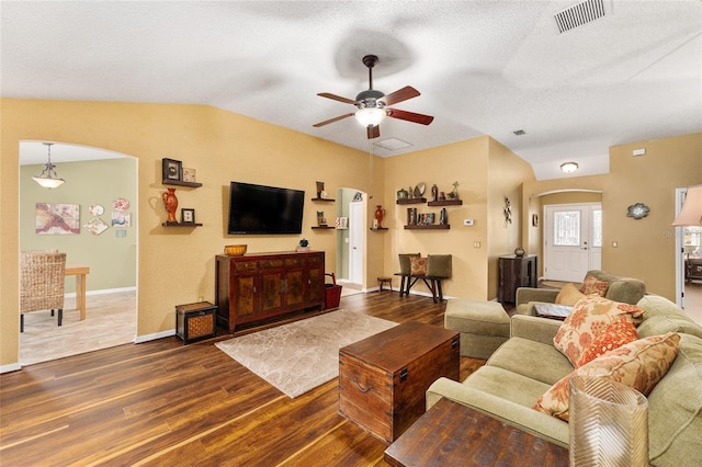 living room featuring ceiling fan, dark hardwood / wood-style flooring, vaulted ceiling, and a textured ceiling