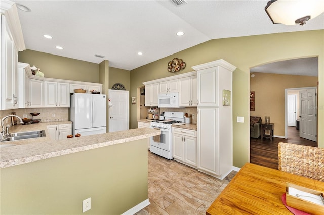 kitchen with white appliances, lofted ceiling, sink, and white cabinets