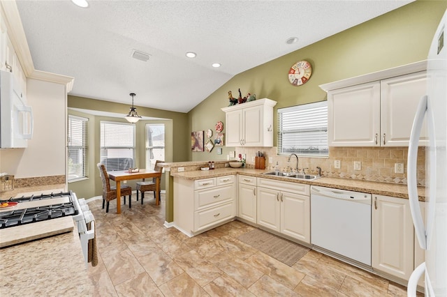 kitchen with pendant lighting, sink, white appliances, vaulted ceiling, and kitchen peninsula