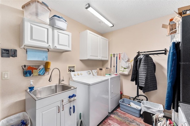 clothes washing area featuring cabinets, washer and clothes dryer, sink, and a textured ceiling