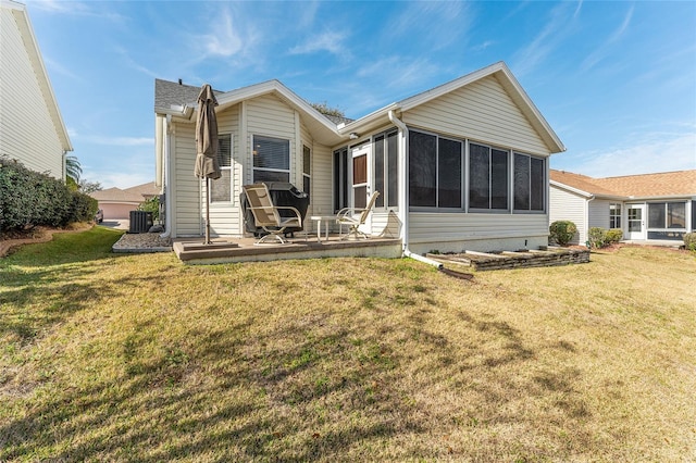 rear view of house with a yard, central AC unit, and a sunroom