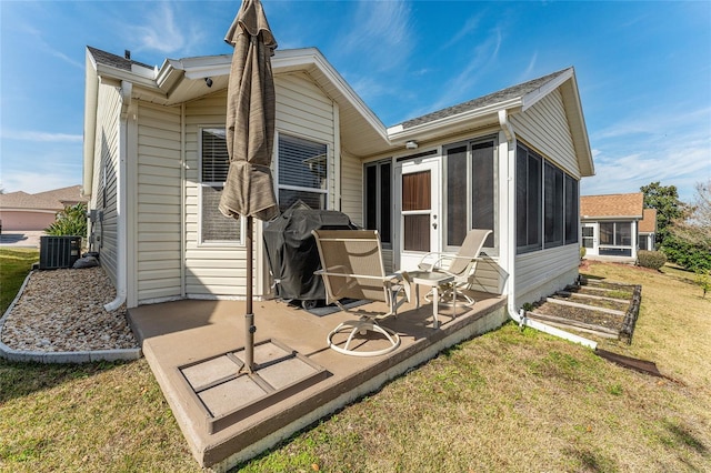 rear view of property featuring a sunroom, a yard, central AC, and a patio area