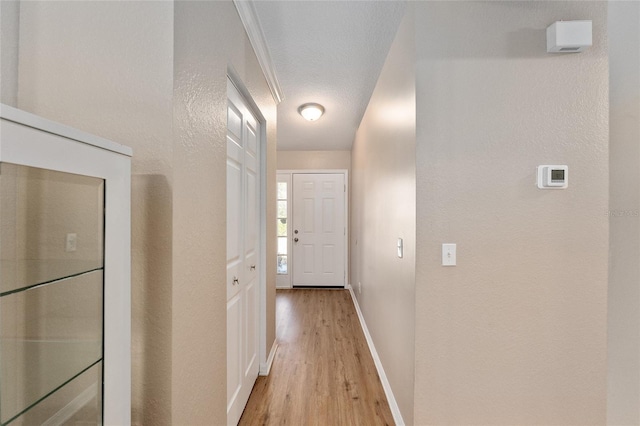 hallway featuring light hardwood / wood-style floors and a textured ceiling