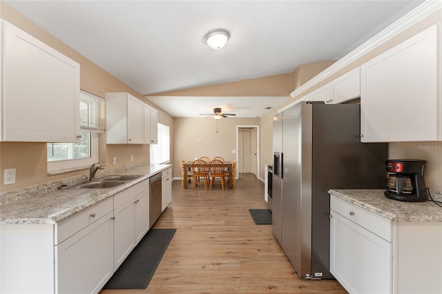 kitchen with vaulted ceiling, appliances with stainless steel finishes, sink, and white cabinets