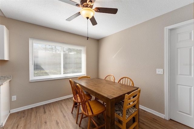 dining area featuring ceiling fan, light hardwood / wood-style floors, and a textured ceiling