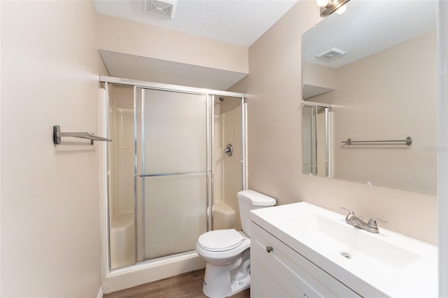 bathroom with hardwood / wood-style floors, an enclosed shower, vanity, a textured ceiling, and toilet