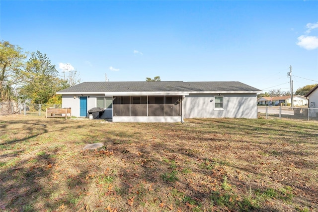 rear view of house featuring a yard and a sunroom