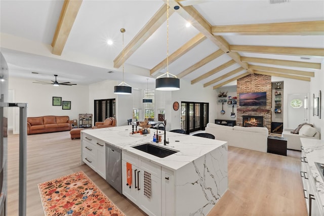 kitchen featuring dishwasher, an island with sink, sink, white cabinets, and hanging light fixtures