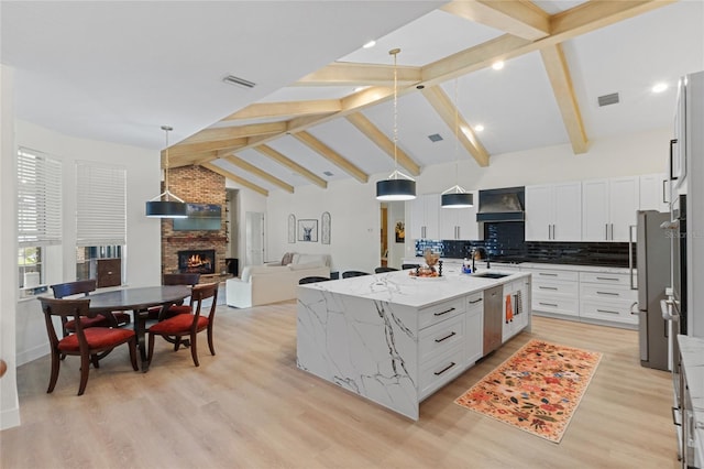 kitchen featuring white cabinetry, sink, a kitchen island with sink, and pendant lighting