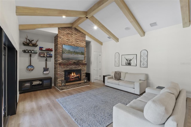 living room with lofted ceiling with beams, a brick fireplace, and light hardwood / wood-style flooring