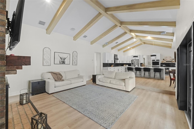 living room with beamed ceiling, high vaulted ceiling, and light hardwood / wood-style flooring