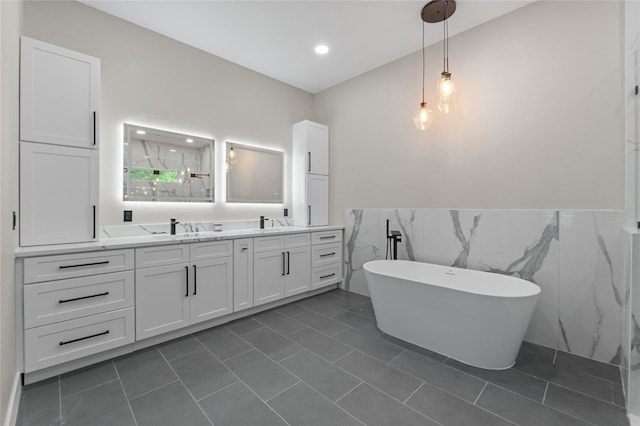 bathroom featuring vanity, a tub to relax in, tile patterned floors, and tile walls