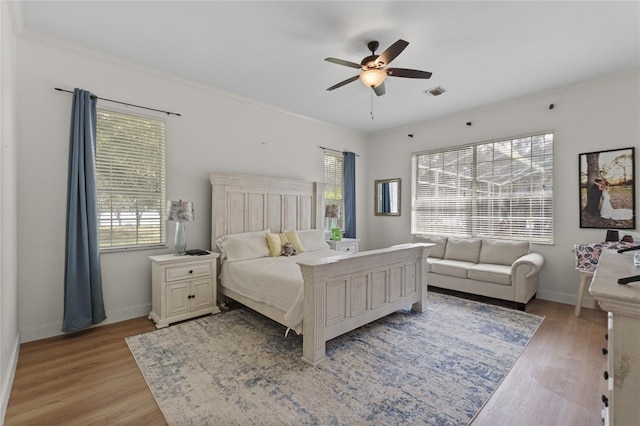 bedroom featuring multiple windows, light hardwood / wood-style floors, and ceiling fan