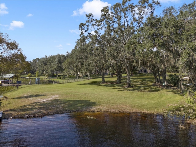 surrounding community with a water view and a lawn