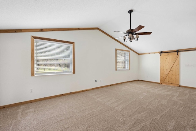 carpeted spare room with ceiling fan, vaulted ceiling, and a healthy amount of sunlight