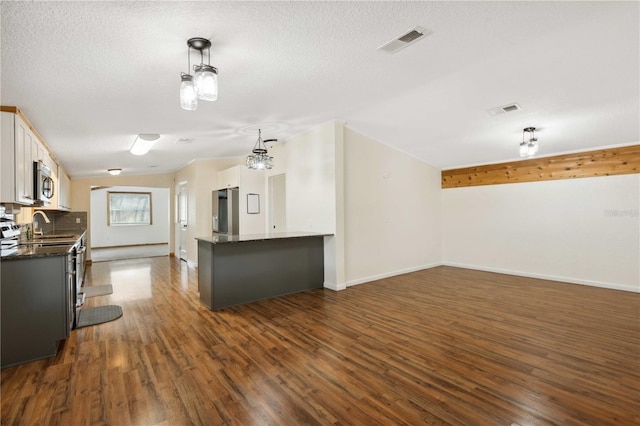 kitchen featuring white cabinetry, hanging light fixtures, a textured ceiling, dark hardwood / wood-style floors, and stainless steel appliances