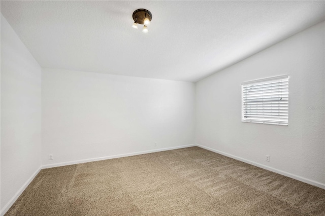 carpeted spare room featuring lofted ceiling