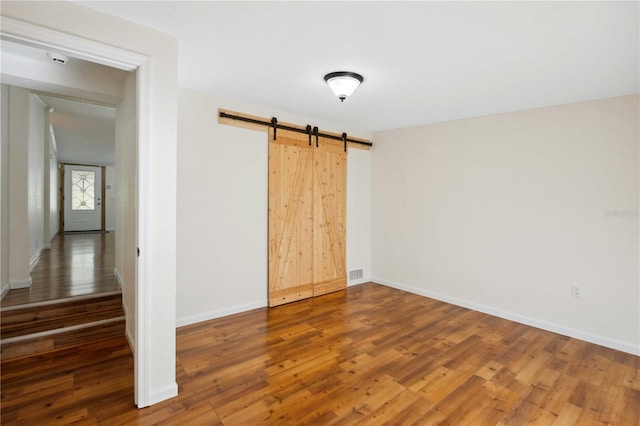 unfurnished room with hardwood / wood-style flooring and a barn door