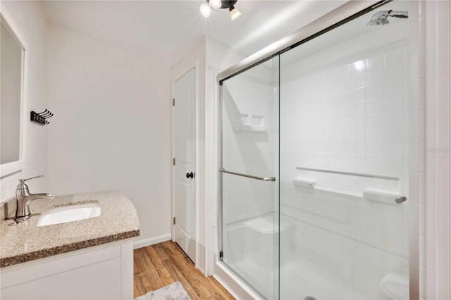 bathroom with wood-type flooring, vanity, and a shower with shower door