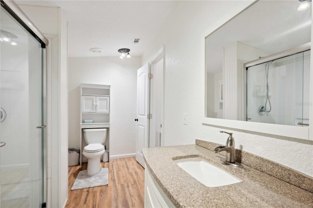 bathroom with vanity, toilet, a shower with door, and hardwood / wood-style floors