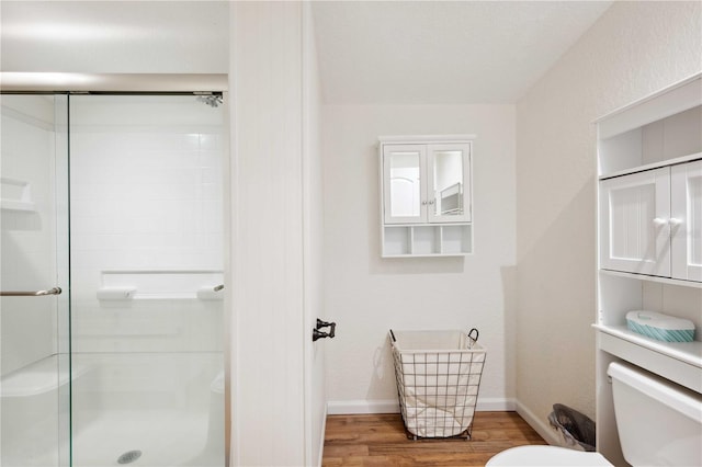 bathroom featuring hardwood / wood-style floors, toilet, and walk in shower