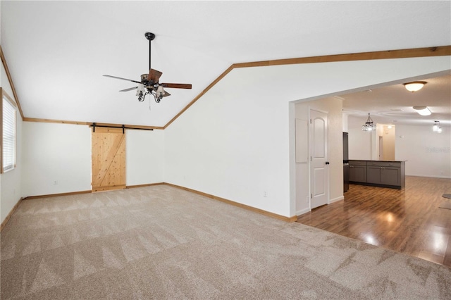 unfurnished living room featuring lofted ceiling, carpet floors, a barn door, and ceiling fan