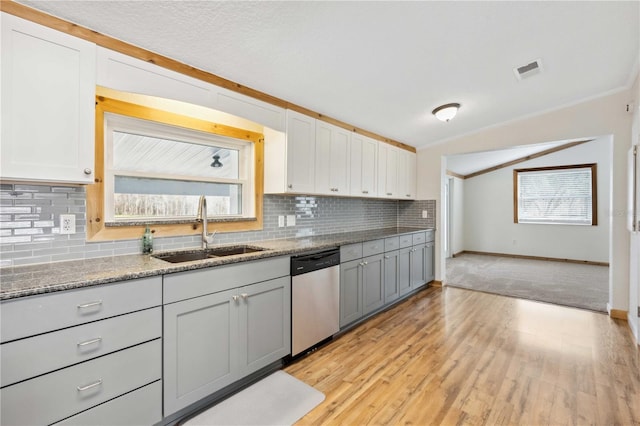 kitchen with white cabinetry, stainless steel dishwasher, sink, and light stone counters