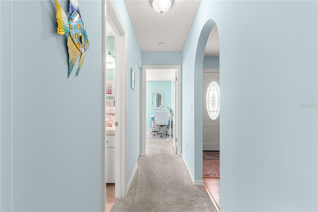 hallway with light carpet and a textured ceiling