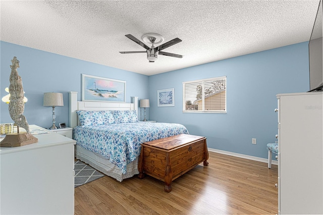 bedroom with hardwood / wood-style floors, a textured ceiling, and ceiling fan