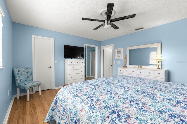 bedroom featuring ceiling fan, light hardwood / wood-style floors, and a textured ceiling