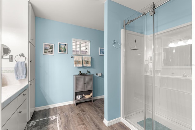 bathroom with hardwood / wood-style flooring, vanity, and a shower with shower door