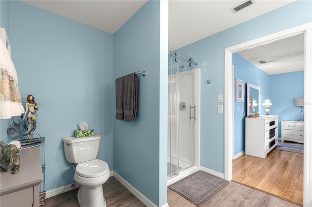 bathroom with hardwood / wood-style flooring, vanity, toilet, and an enclosed shower