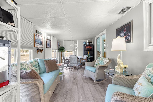 living room featuring a healthy amount of sunlight, a paneled ceiling, and light hardwood / wood-style floors