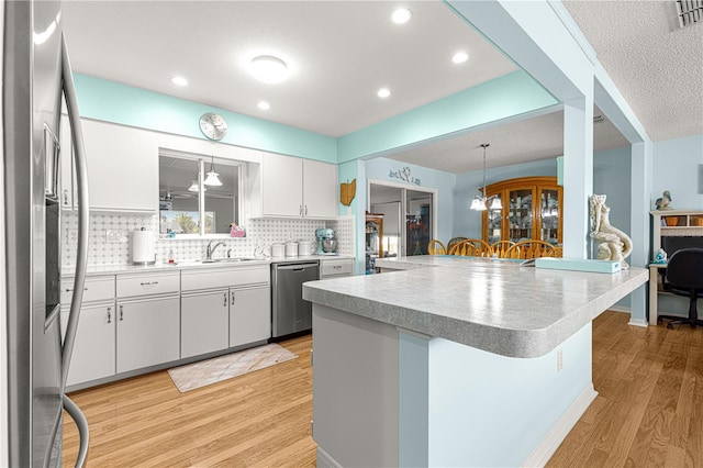 kitchen with a breakfast bar, white cabinetry, hanging light fixtures, stainless steel appliances, and kitchen peninsula