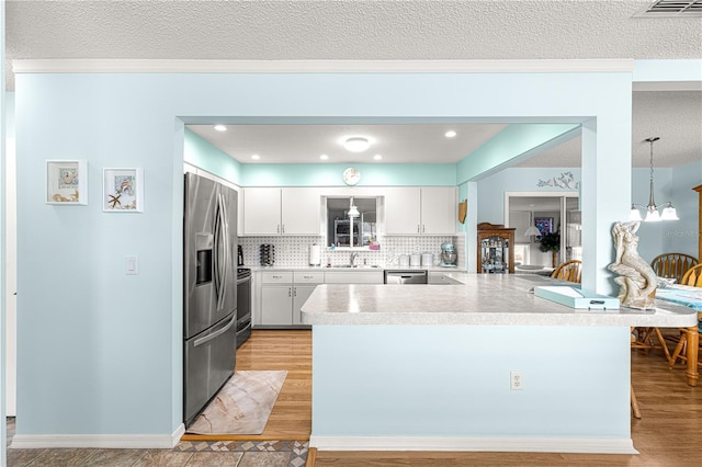 kitchen with stainless steel appliances, white cabinetry, pendant lighting, and kitchen peninsula