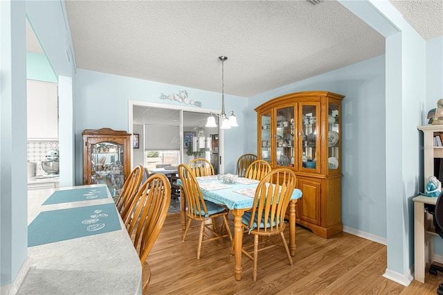 dining area featuring a textured ceiling, a chandelier, and light hardwood / wood-style flooring