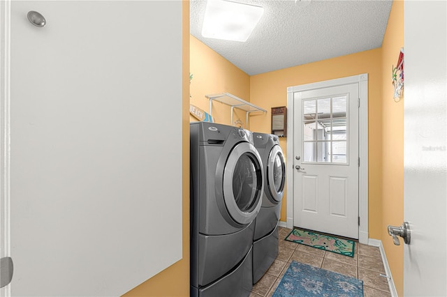 clothes washing area featuring separate washer and dryer, a textured ceiling, and light tile patterned floors