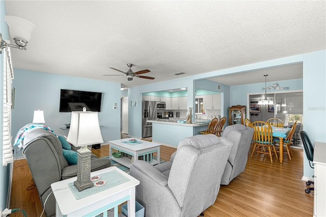 living room with ceiling fan, light hardwood / wood-style flooring, and a textured ceiling