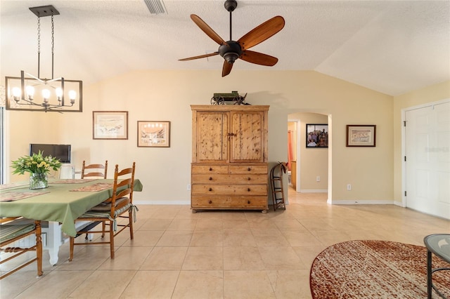 dining space with light tile patterned floors, ceiling fan with notable chandelier, vaulted ceiling, and a textured ceiling