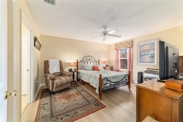 bedroom with ceiling fan, a textured ceiling, and light hardwood / wood-style floors
