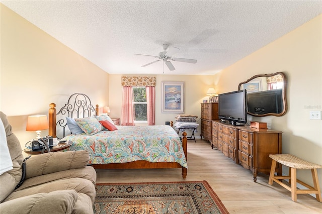 bedroom with ceiling fan, light hardwood / wood-style floors, and a textured ceiling