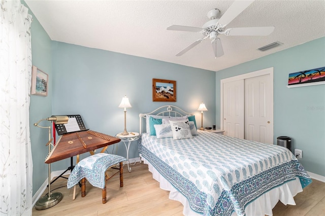 bedroom with ceiling fan, light hardwood / wood-style floors, a closet, and a textured ceiling