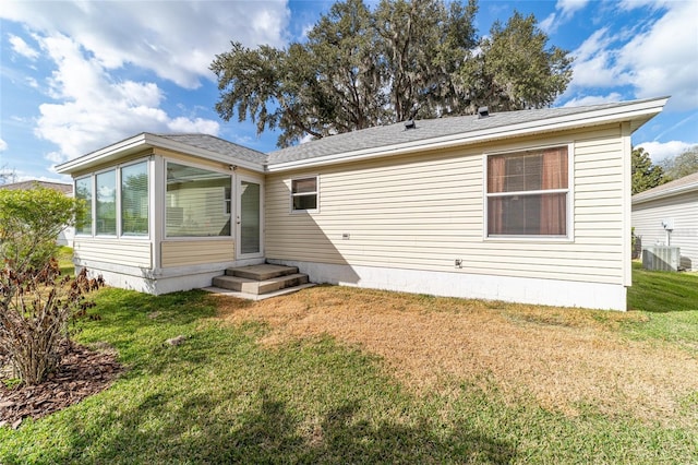 rear view of property featuring central air condition unit and a lawn